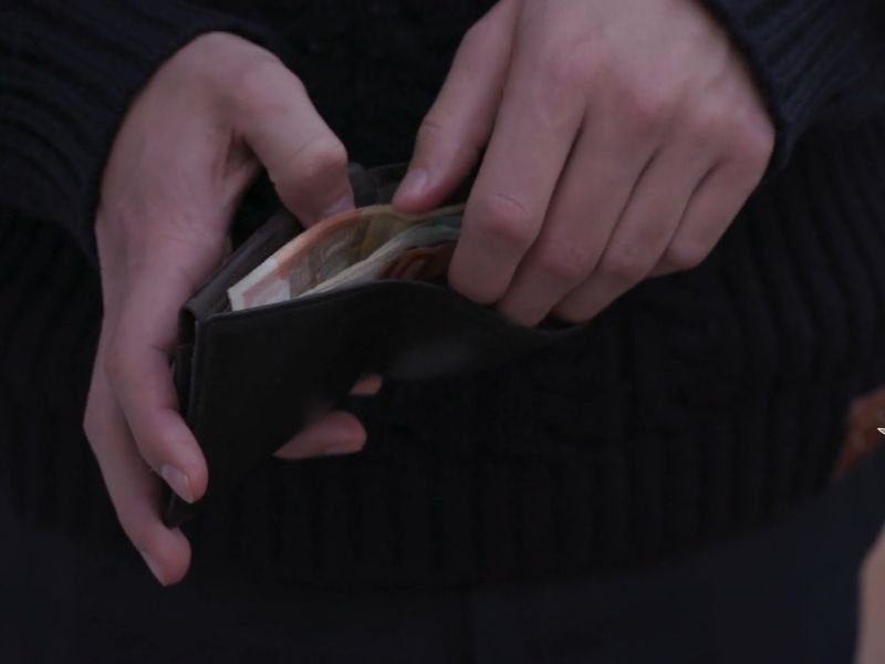 Osoba drži novčanik u ruci i broji novac