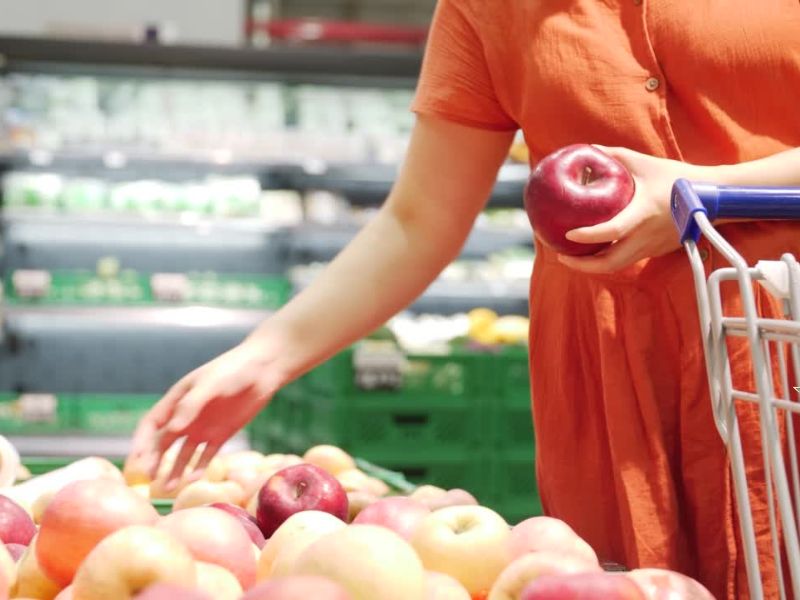 Osoba srednjih godina u marketu bira jabuke