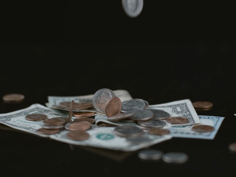Novčanice stoje na crnoj pizadini a kovanice padaju iz visa
